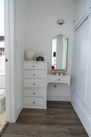 A white vanity with a mirror, drawers, and a small plant. - Urban Studio in Korea Town (Los Angeles)