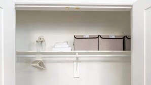 A walk-in closet with a white door, a hanging rack, and a wooden floor.