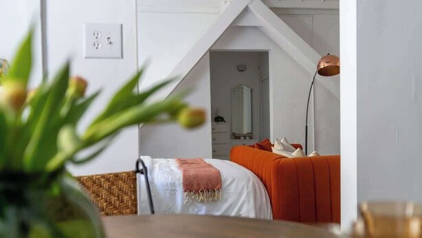 A bedroom with a bed, a nightstand, a lamp, and a view of a hallway.