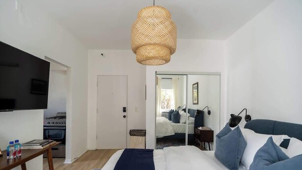 Un dormitorio con cama, mesita de noche y televisor.