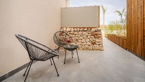 A patio with two chairs, a small table, and a stone wall.