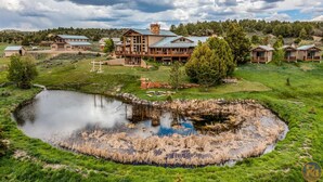 A large lodge with multiple guest rooms, a central building with a chimney, and a pond in the foreground. - The Wildflower, Lodge+guest cabins 26 people (Alton)