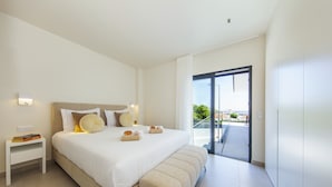 A modern bedroom with a large bed, a nightstand, and a view of the outdoors through a sliding door. - Albufeira villa w/ heatable pool & sea views (Albufeira)