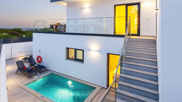 A modern two-story building with a rooftop pool area, outdoor seating, and a staircase leading to the upper floor. - Albufeira villa w/ heatable pool & sea views (Albufeira)