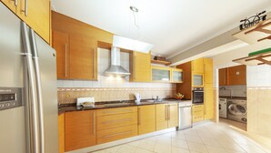 A modern kitchen with wooden cabinets, stainless steel appliances, and a tiled floor. - Cozy villa with heatable pool and BBQ (Carvoeiro)