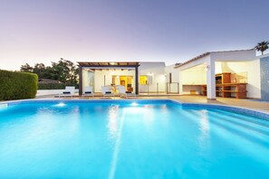 Una casa moderna con piscina, terraza cubierta y zona de cocina.