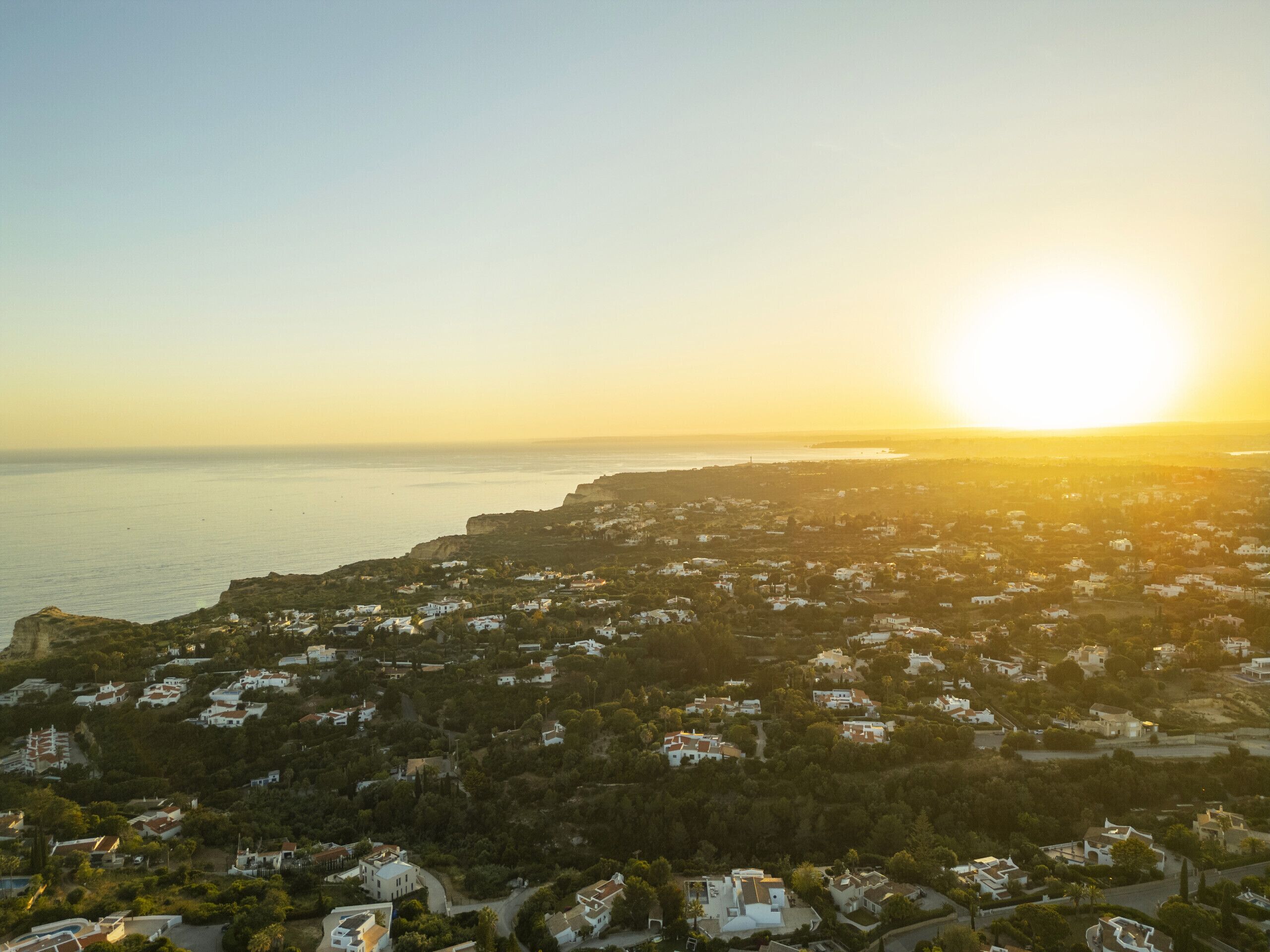 A coastal town with houses and a view of the sea during sunset.