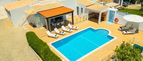 A rooftop pool area with lounge chairs, a covered seating area, and a swimming pool.