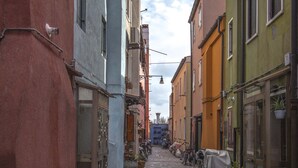 Eine enge Kopfsteinpflasterstraße gesäumt von bunten Häusern, mit an den Seiten abgestellten Fahrrädern und Wäsche, die zum Trocknen aufgehängt ist.