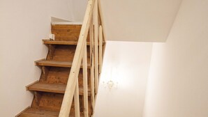 Eine Holztreppe mit schlichtem Geländer und einer Wandleuchte.