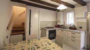 Eine kompakte Küche mit Einbauherd, Spüle und Kühlschrank. Eine Holztreppe führt zu einer weiteren Ebene.