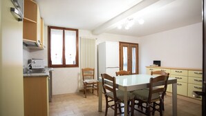 A compact kitchen with a dining table and chairs, a built-in oven, and a refrigerator. - Dimora Alba di Mare -apeliving- Pellestrina Ve (Venezia)