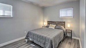 A bedroom with a bed, nightstands, a window, and a ceiling light. - Cozy Home with a Huge Backyard! (Parma Heights)