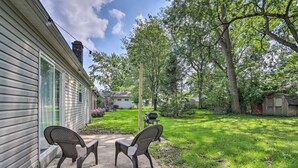 A house with a covered patio, two wicker chairs, and a grill in the backyard. - Cozy Home with a Huge Backyard! (Parma Heights)
