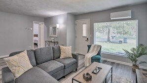 A living room with a grey sectional sofa, a teal armchair, a coffee table, and a large window with blinds. - Cozy Home with a Huge Backyard! (Parma Heights)