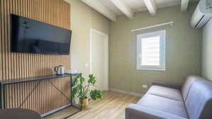 Een moderne woonkamer met een houten wandpaneel, een flatscreen televisie, een bank, een salontafel en een potplant.