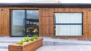 Een modern gebouw met houten lambrisering, grote glasramen en een ingebouwde plantenbak met groene planten.