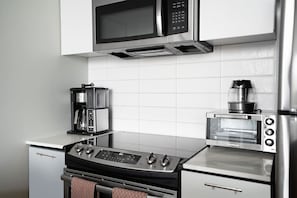 Een moderne keuken met een roestvrijstalen fornuis, een koffiezetapparaat, een magnetron en een elektrische oven.