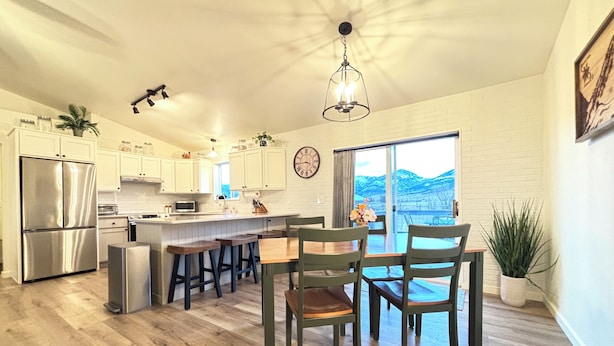 A modern kitchen with a central island, stainless steel appliances, and a large window offering a view of the outdoors. - Bridger Mountain View Farmhouse  (Belgrade)
