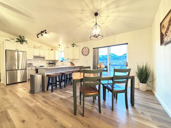 A modern kitchen with a central island, stainless steel appliances, and a large window offering a view of the outdoors.