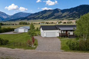 A rural property with a gravel driveway, a white garage, and a small building with a porch.