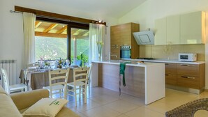 A modern kitchen with a central island, wooden cabinets, and a built-in oven. - Acquanera 6&2 by Marche Holiday Villas (Piobbico)