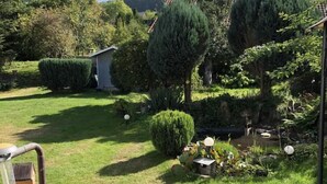 Un jardín bien cuidado con diversas plantas y un cobertizo pequeño.
