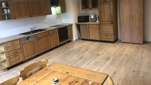 Cocina pequeña con armarios de madera, una mesa de comedor y un microondas.
