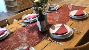 Un comedor con una mesa de madera dispuesta para cuatro personas, un jarrón con flores y armarios de madera al fondo.