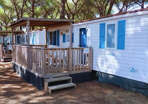 A mobile home with a wooden porch and a 'Happy Camp' sign.