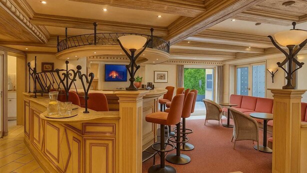 A spacious, elegantly designed hotel lobby with a curved bar, comfortable seating, and a television. - AR Boutique Hotel Mannheim City (Mannheim)