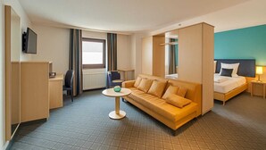 A hotel room with a sofa, a bed, a desk, and a TV. - AR Boutique Hotel Mannheim City (Mannheim)