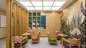 A library with bookshelves, seating, and a mural.