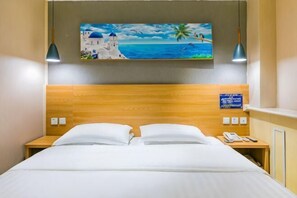 A hotel room with a wooden headboard, a painting of a coastal scene, a nightstand with a phone, and a sign indicating amenities. - Super 8 Hotel (Beijing Xizhimen) (Beijing)