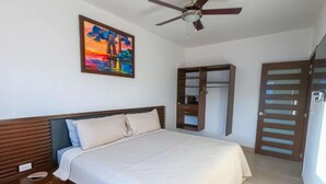 Une chambre à coucher avec un lit, une armoire, un ventilateur de plafond et un tableau accroché au mur.