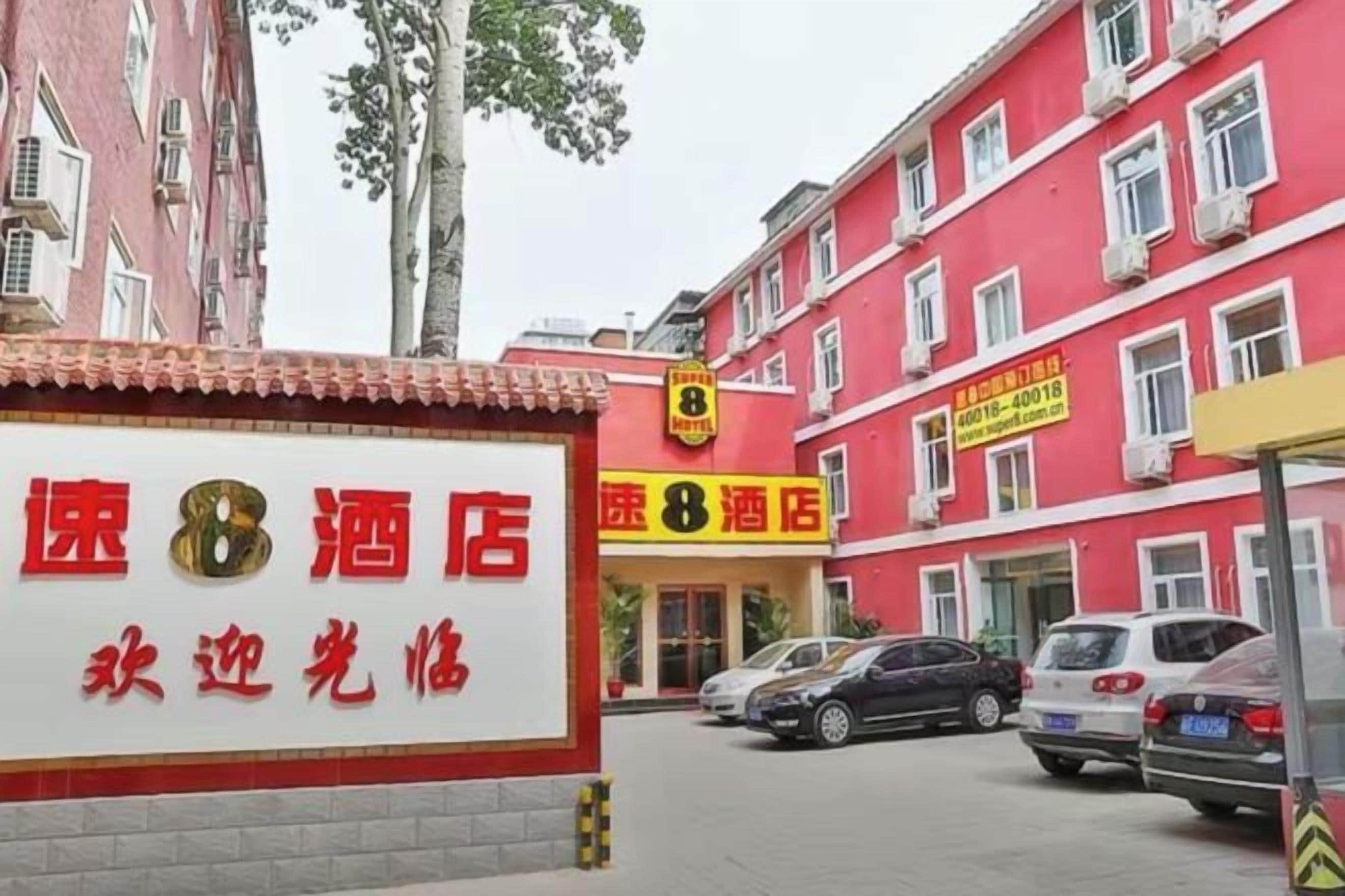 Un hotel con fachada roja, múltiples ventanas y un letrero con texto.