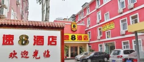 A hotel with a red facade, multiple windows, and a signboard with text.