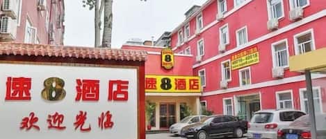 Un hotel con fachada roja, múltiples ventanas y un cartel.