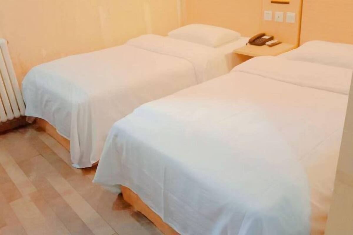 Una habitación de hotel con dos camas individuales, una mesita de noche con teléfono y un radiador.