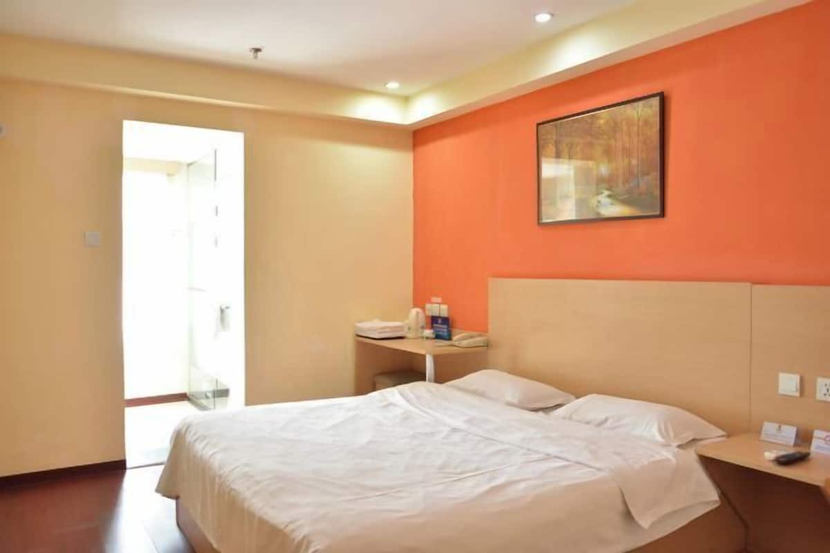 Una habitación de hotel con una cama, un escritorio, una silla y un cuadro en la pared.