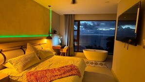 A modern bedroom with a large bed, a vanity, a bathtub, and a view of the ocean. - San Juan del Sur Villa | Infinity Pool Sunset View (San Juan del Sur)
