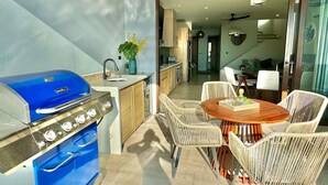 A patio with a blue grill, wicker chairs, and a dining table. - San Juan del Sur Villa | Infinity Pool Sunset View (San Juan del Sur)