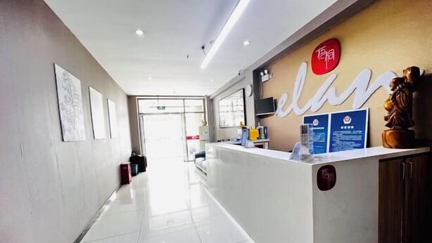 A hotel reception area with a modern design, featuring a reception desk, framed artwork on the walls, and a clear view of the entrance. - Wutong Hotel (Beijing Changping University of Petroleum) (Beijing)