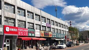 A row of commercial buildings with storefronts, a clear sky, and a street with parked vehicles.