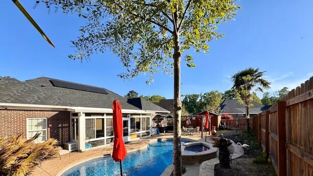 A backyard with a swimming pool, a covered patio, and a wooden fence. - Entire Home Augusta, Martinez GA with Swimming pool (Martinez)