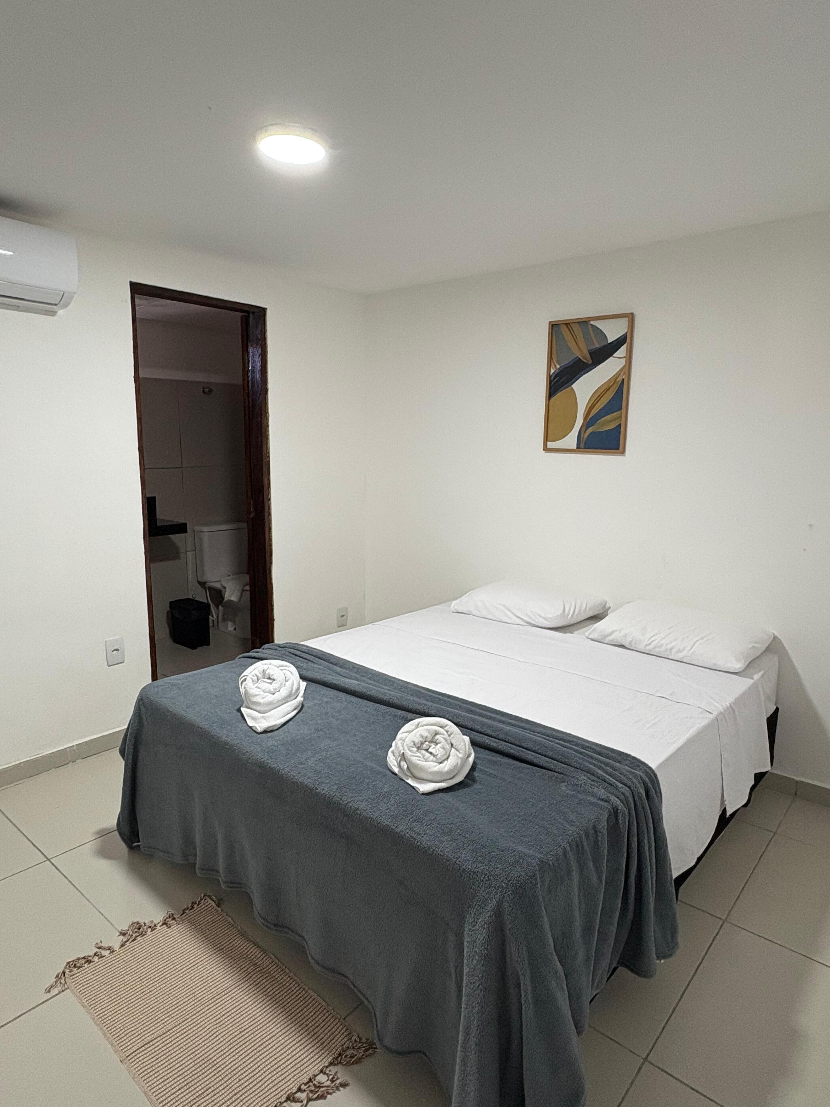 Una habitación de hotel con una cama, un cuadro en la pared y una puerta que da al baño.