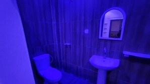 A bathroom with a toilet and a sink, tiled walls, and a mirror above the sink.