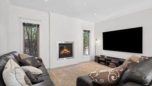 Una sala de estar moderna con chimenea, sofás de cuero, un televisor de pantalla plana y una estantería.