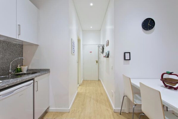 Enter a well-appointed hallway leading to a dining area with a kitchenette and a cozy dining table for two.