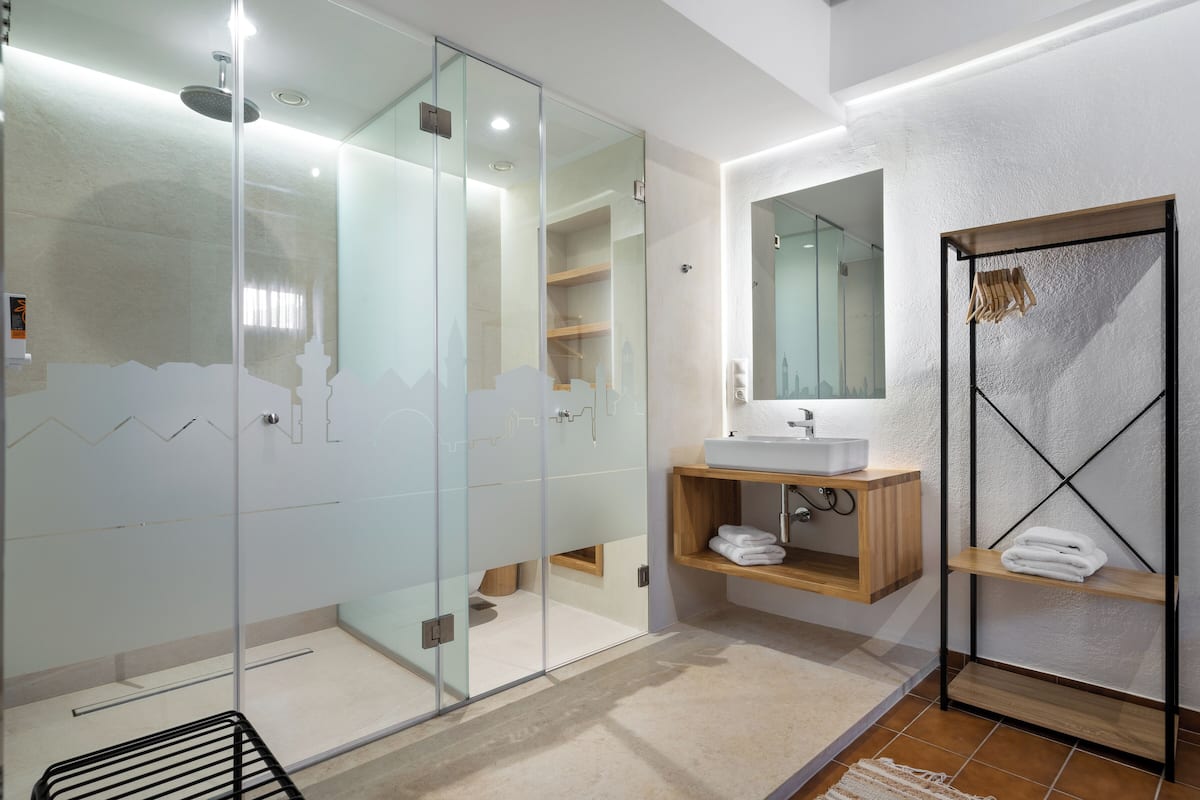 A modern bathroom with a glass-enclosed shower, a wooden vanity with a sink, and a towel rack.
